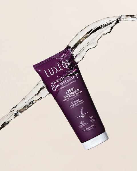 Purple Luxeol matu kopšanas produkts ar ūdens šļakatām uz bēša fona