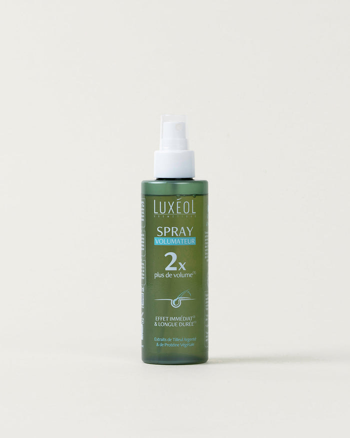 Green spray bottle with white cap on a light beige background