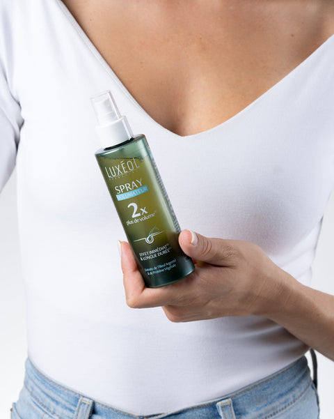 Persona, kas tur izsmidzināmu miglu Luxe Oil pret baltu fona